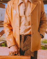 a man in a tan leather jacket holding a briefcase